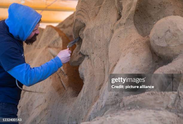 April 2021, Mecklenburg-Western Pomerania, Warnemünde: Dmitry Klimenko from Russia works on his sculpture for the 11th Warnemünde Sand World under...