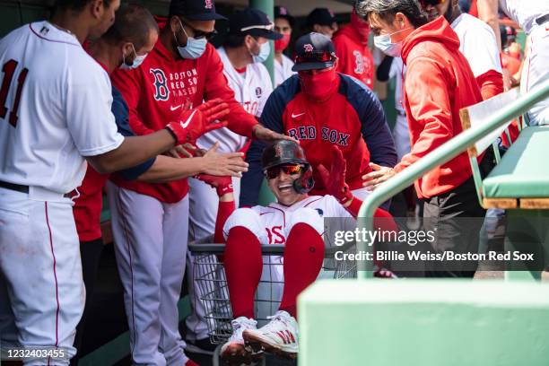 Enrique Hernandez of the Boston Red Sox reacts as he is pushed in a laundry cart after hitting a solo home run during the first inning of a game...