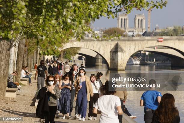 People walk on the banks of the river Seine before the curfew, aimed to curb the spread of the Covid-19, in Paris on April 19, 2021.