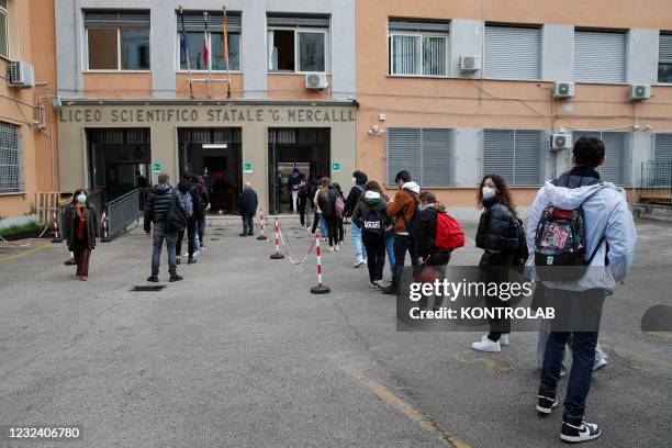 Students wearing protective masks are next to the entrance of a high school. Today high schools reopened after months of closure due to the increase...