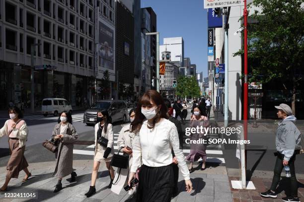 Pedestrians wearing face masks as a preventive measure against the spread of Covid-19 walk over a crossroad inside the popular Ginza commercial...