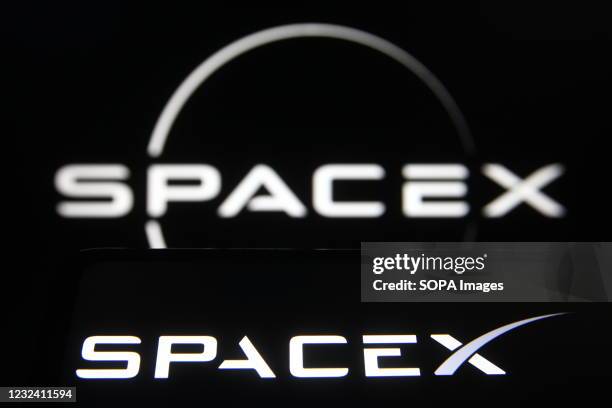 In this photo illustration a SpaceX logo of an US aerospace company is seen on a smartphone and a pc screen.