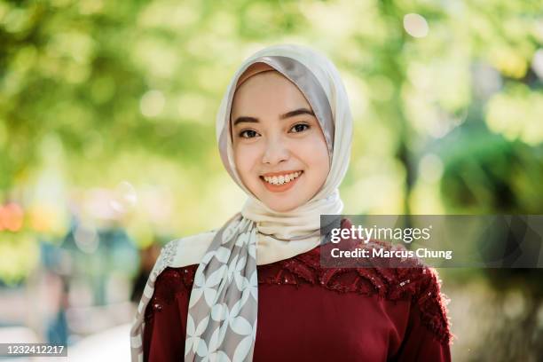 porträt einer asiatischen jungen malay hijab frau glücklich mit zu schüchternem lächeln und blick in die kamera - malay hijab stock-fotos und bilder