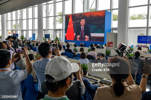 Journalists watch a screen showing China's President Xi Jinping delivering a speech during the opening of the Boao Forum for Asia Annual Conference...