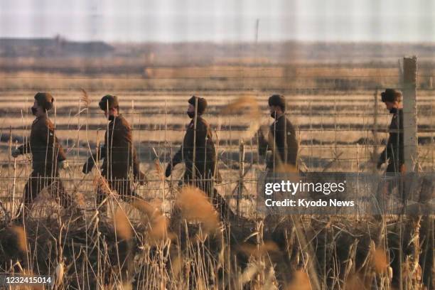 This photo taken from the Chinese city of Dandong shows North Korean soldiers patrolling a border area with China on March 22, 2021.