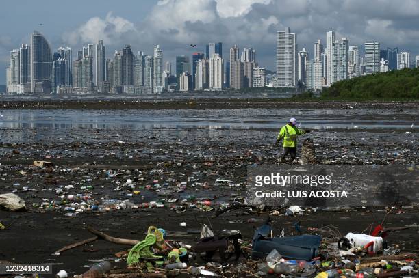 Man collects garbage, including plastic waste, at the beach of Costa del Este, in Panama City, on April 19, 2021. - Every two weeks, Marine Biology...