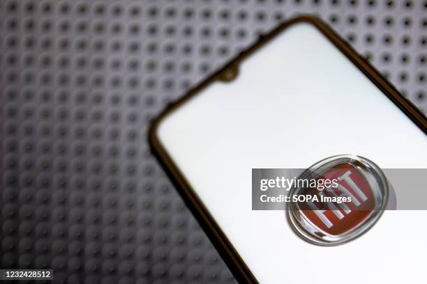 In this photo illustration a Fiat logo seen displayed on a smartphone screen with a computer wallpaper in the background.