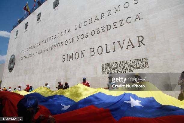 Supporters of the Venezuelan government hold a giant flag during a march through the city streets of the libertarian and Bolivarian torch to...