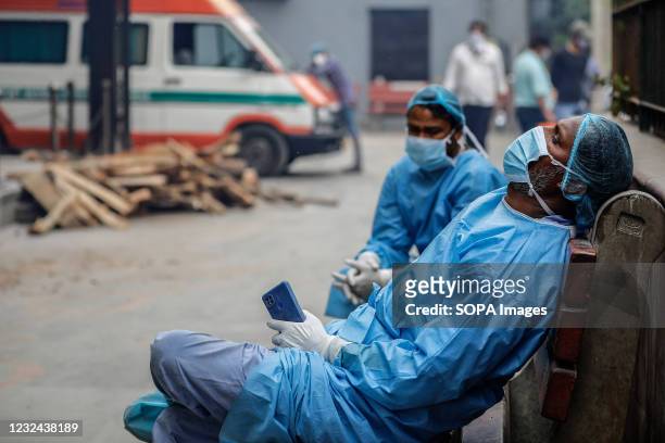 Cemetery workers helping people to cremate the bodies of their relatives who died of the Covid-19 coronavirus disease take a break at a crematorium,...