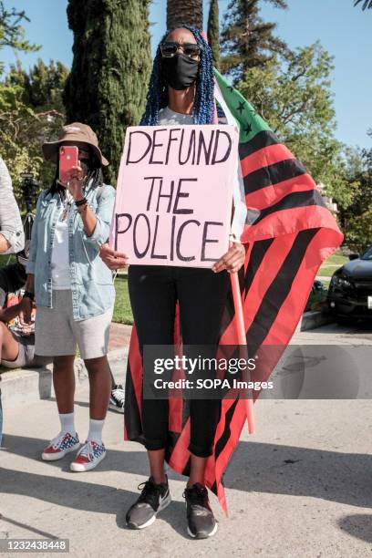 Protester holds a placard that says, Defund The Police during the demonstration. Hours after the verdict of the Derek Chauvin trial, protesters meet...