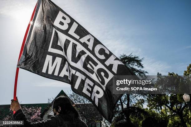 Protester waves a Black Lives Matter flag during the demonstration. Hours after the verdict of the Derek Chauvin trial, protesters meet outside of...