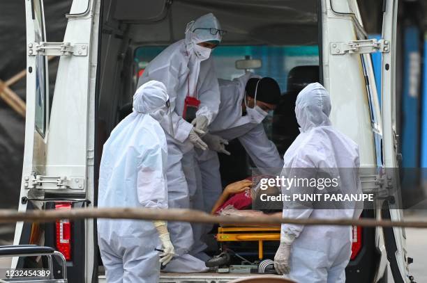 Health workers wearing Personal Protective Equipment gears help a patient inside an ambulance at a recovery centre to treat Covid-19 coronavirus...