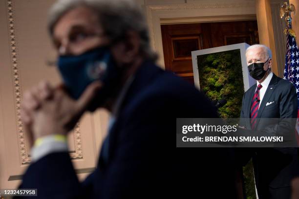 Envoy for climate John Kerry and US President Joe Biden listen during climate change virtual summit from the East Room of the White House campus...