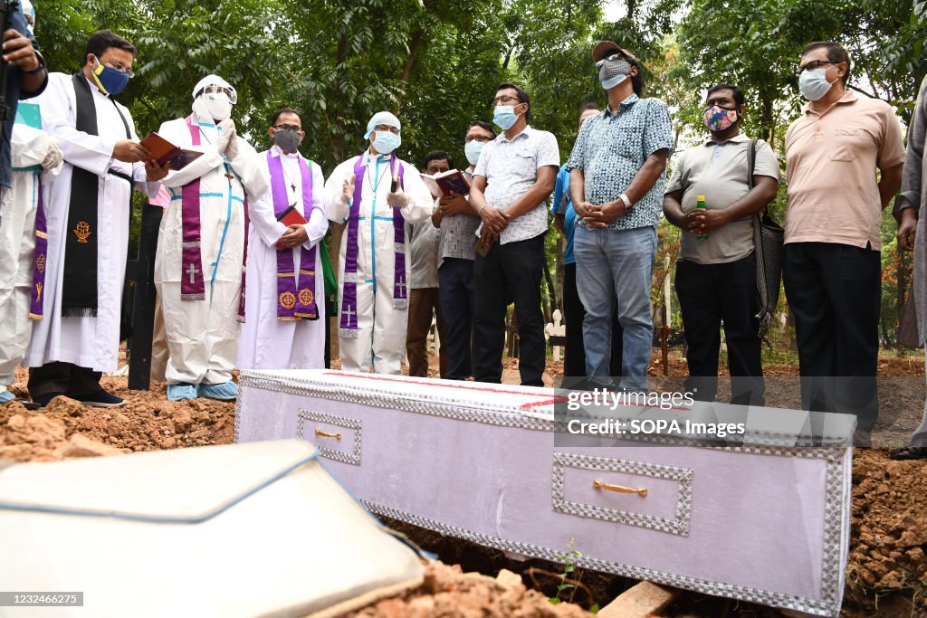 Mourners standing next to the coffin with the covid 19...