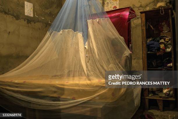 Woman rests wrapped in a mosquito net to protect herself from mosquitos which can transmit malaria at her house in Barcelona, Anzoategui State,...