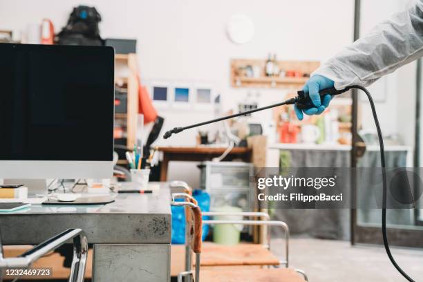 sanitation worker in protective suit is disinfecting office desk before the reopening of the business - pest control equipment stock pictures, royalty-free photos & images