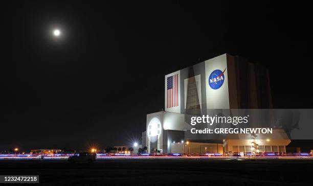 The moon helps illuminate the Vehicle Assembly Building at the Kennedy Space Center as the motorcade carrying the Crew-2 mission astronauts to launch...