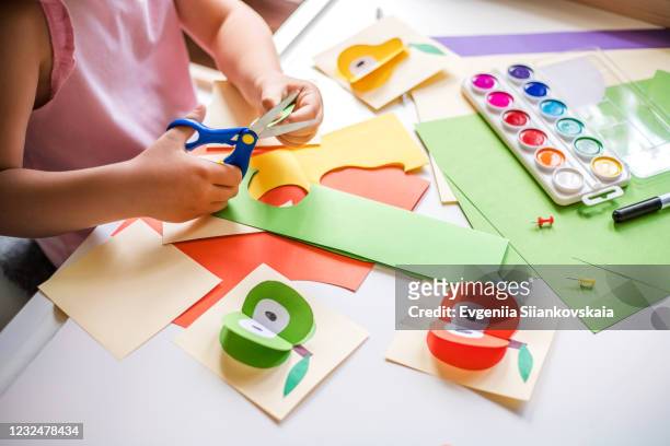 little girl cutting colorful paper at the table. - craft stock-fotos und bilder