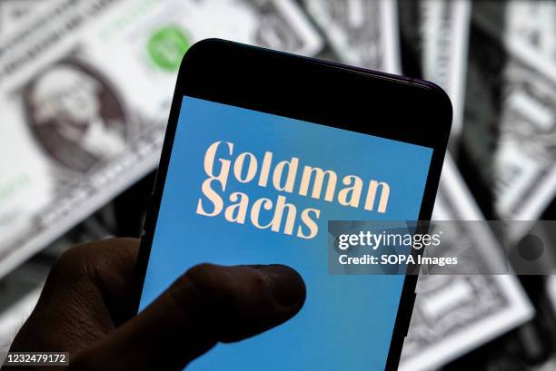 In this photo illustration the Goldman Sachs logo seen on an Android mobile device screen with the currency of the United States in the background.