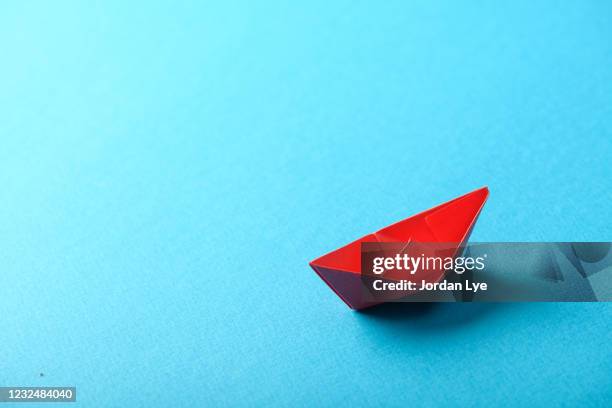 red origami boat on blue background. - origami boat stock pictures, royalty-free photos & images