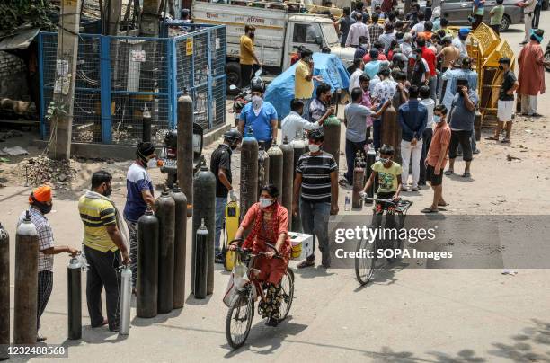 Family members of Covid-19 infected patients stand in a queue with empty oxygen cylinders outside the oxygen filling center in New Delhi. India is...