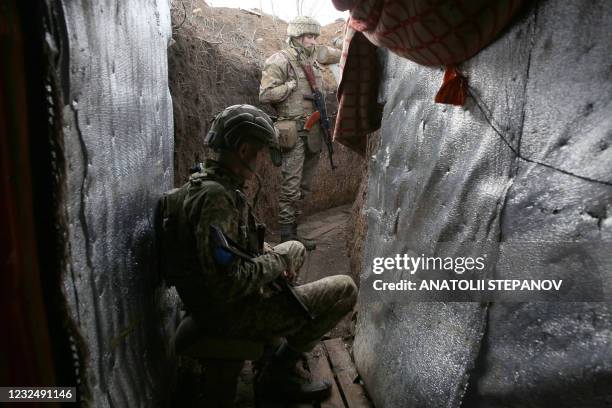 Ukrainian servicemen wait in a trench on the frontline with Russia-backed separatists near town of Krasnogorivka, Donetsk region, on April 23, 2021....