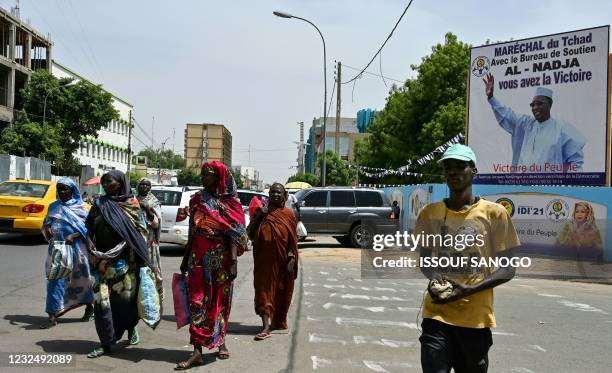 People walks past a poster of Chad's late president Idriss Deby in a street in Ndjamena on April 24 a day after his funeral. - Chad's President...