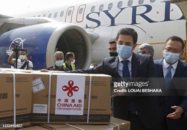 Syrian Health Minister Hassan al-Ghabash and the Chinese Ambassador Feng Biao oversee the unloading of aid boxes containing the Sinopharm Covid-19...