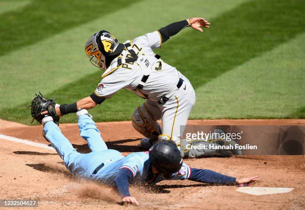 Jake Cave of the Minnesota Twins slides safely into home plate as Michael Perez of the Pittsburgh Pirates fields the throw during the eighth inning...