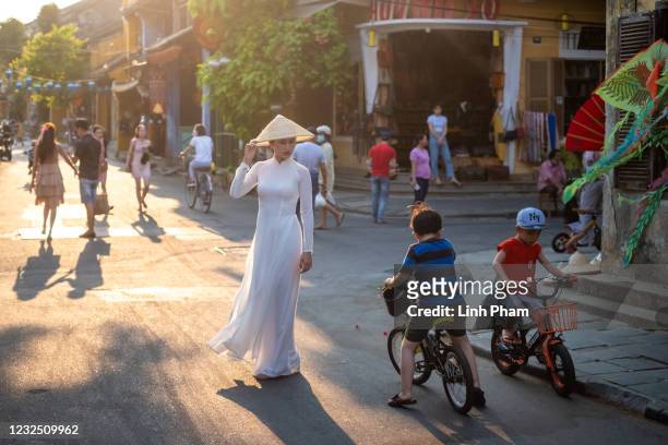 Lady in traditional 'áo dài' and conical hat, poses for photos on the street of Hoi An ancient town on April 24, 2021 in Hoi An, Vietnam. Hoi An, a...