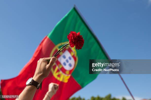 People march holding up red carnations and the Portuguese flag to commemorate the anniversary of the Portugal's revolution, in Lisbon, Portugal, on...