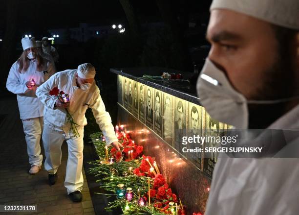 Chernobyl plant employee lights candles and lays flowers at the monument to Chernobyl victims in Slavutych, the city where the power station's...