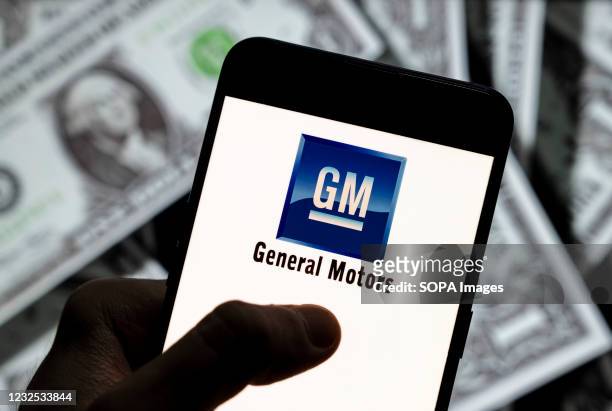 In this photo illustration, a General Motors logo seen displayed on a smartphone with USD currency in the background.