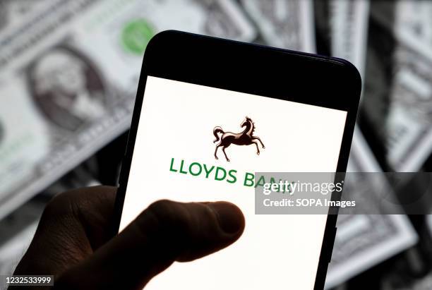 In this photo illustration, a Lloyds Bank plc logo seen displayed on a smartphone with USD currency in the background.