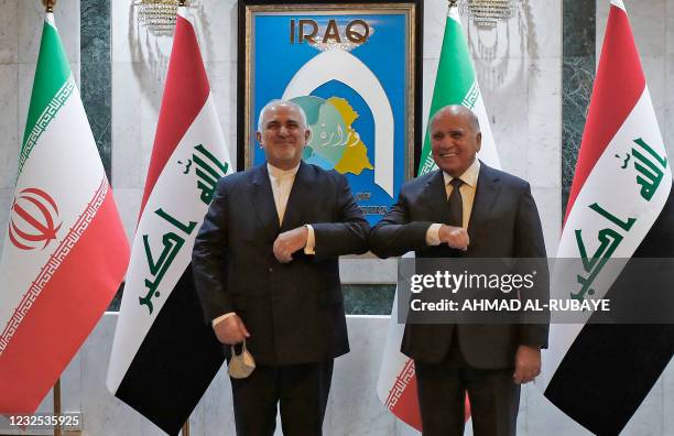 Iraqi Foreign Minister Fuad Hussein elbow-bumps his Iranian counterpart Mohammad Javad Zarif during a reception for the latter in the capital Baghdad...