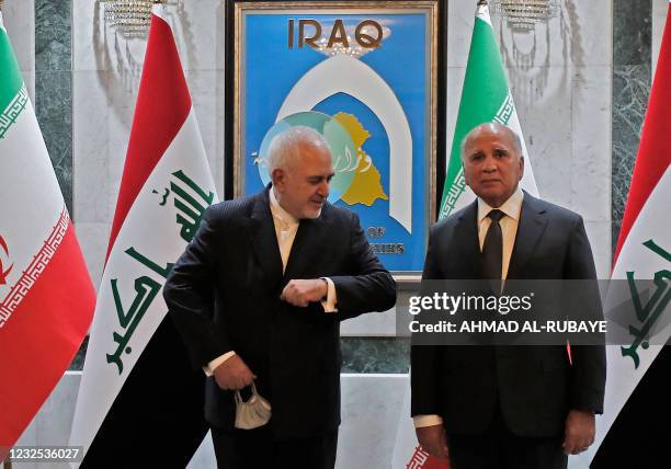 Iran's Foreign Minister Mohammad Javad Zarif tries to elbow-bump his Iraqi counterpart Fuad Hussein during a reception for the former in the capital...