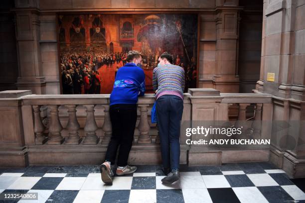 Visitors wearing face coverings look at exhibits in the re-opened Kelvingrove Art Gallery and Museum in Glasgow on April 26, 2021 following the...