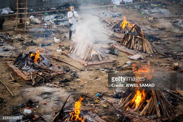 Man prays next to a burning pyre of a victim who died of the Covid-19 coronavirus at a cremation ground in New Delhi on April 26, 2021.