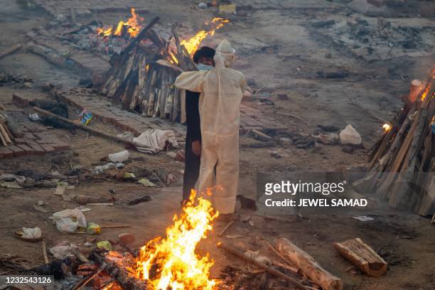 Family members embrace each other amid burning pyres of victims who lost their lives due to the Covid-19 coronavirus at a cremation ground in New...