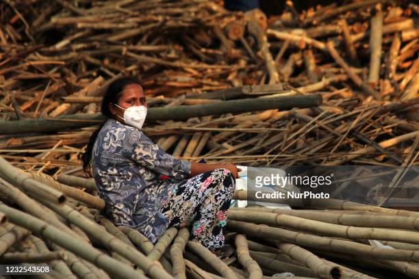 Relative mourns as she sits next to the burning funeral pyres during a mass cremation of victims, who died due to the coronavirus disease, at a...