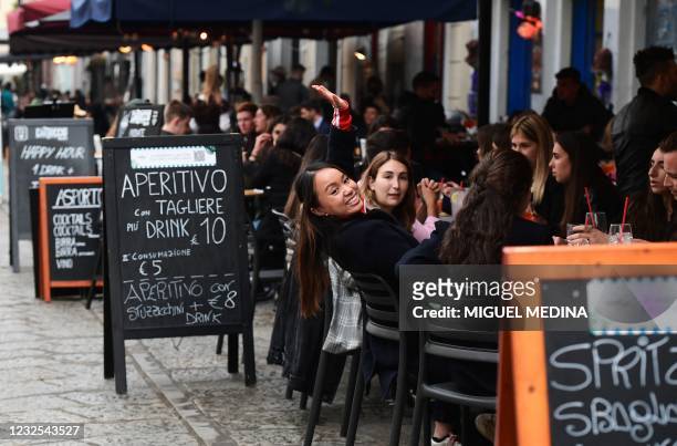 People have a drink on a bar terrace at the Navigli in downtown Milan on April 26, 2021 as bars, restaurants, cinemas and concert halls partially...