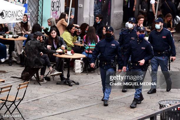 Police patrol by people having a drink on a bar terrace at the Navigli in downtown Milan on April 26, 2021 as bars, restaurants, cinemas and concert...