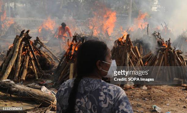 Family member looks on as several funeral pyres of those patients who died of COVID-19 disease burn up during the mass cremation at Ghazipur...