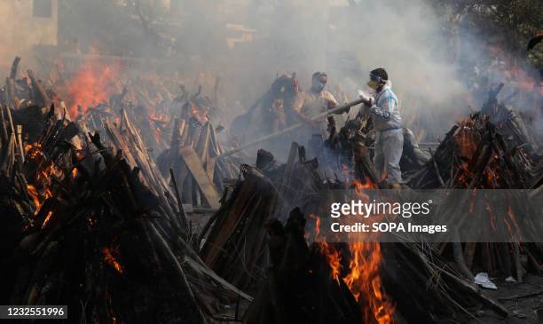Relatives stand next to the burning funeral pyres of those who died due to the coronavirus disease , at Ghazipur cremation ground in New Delhi. In...
