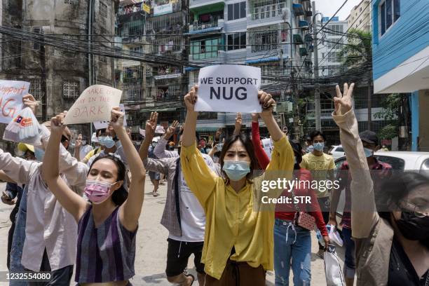 Protesters hold signs in support of the National Unity Government during a demonstration against the military coup in Yangon's Sanchaung township on...