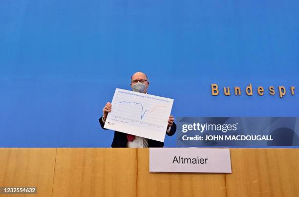 German Economy Minister Peter Altmaier holds a graph during a press conference to present the German government's economic spring projection on April...