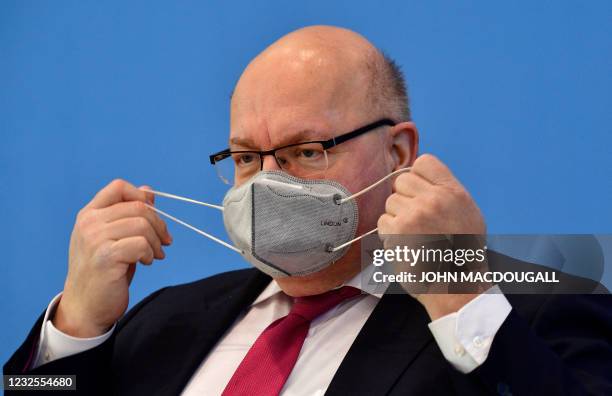 German Economy Minister Peter Altmaier takes off his face mask as he arrives to present the German government's economic spring projection on April...
