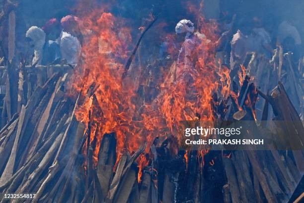 Family members and relatives perform the last rites amid the funeral pyres of victims who died of the Covid-19 coronavirus during mass cremation held...