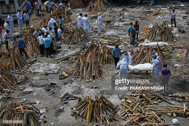 Family members and relatives prepare the funeral pyre of victims who died of the Covid-19 coronavirus during mass cremation held at a crematorium in...