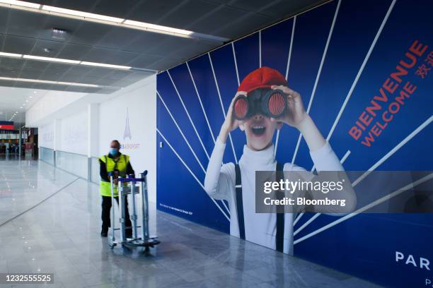 An airport worker wheels luggage trolleys in Terminal 3 at Orly Airport, operated by Aeroports de Paris, in Paris, France, on Tuesday, April 27,...